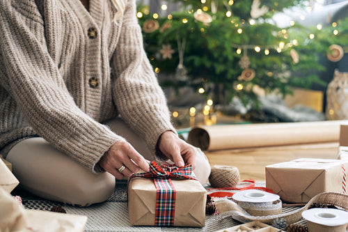 Unrecognizable caucasian woman wrapping Christmas gifts on the floor