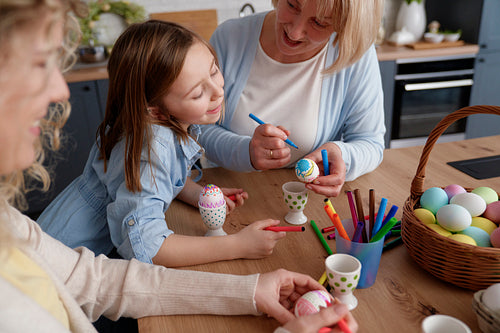 Three generations of women have fun during painting Easter eggs