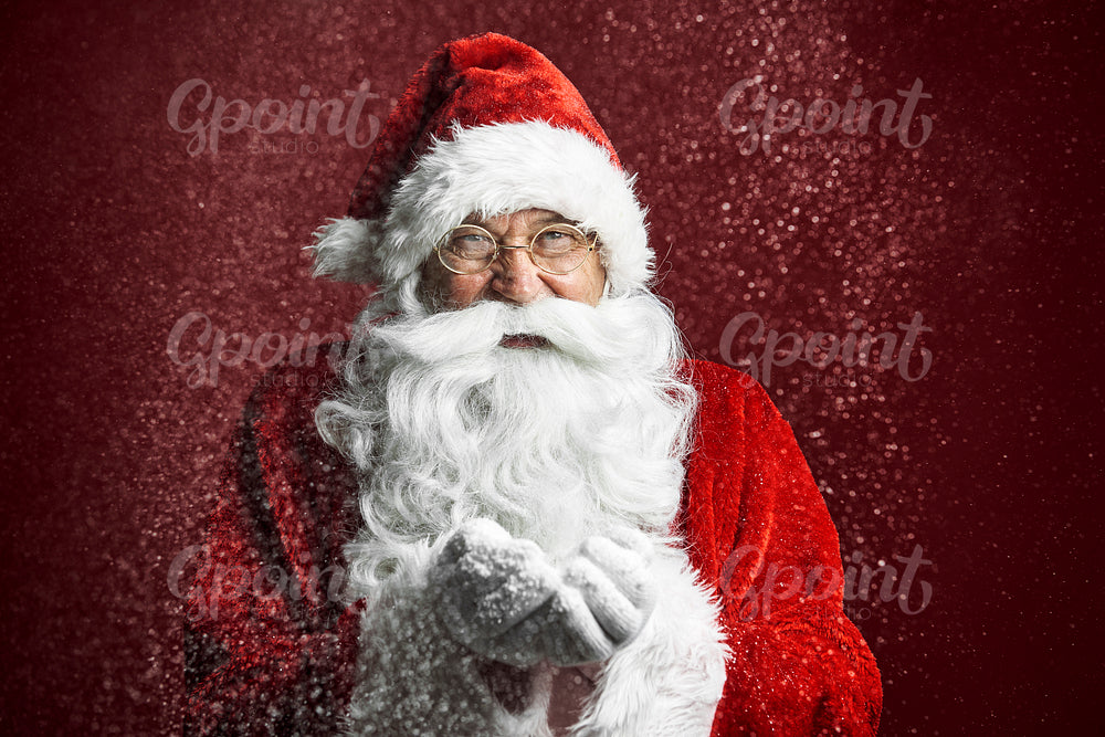 Close up of caucasian Santa Claus on red background blowing snow 