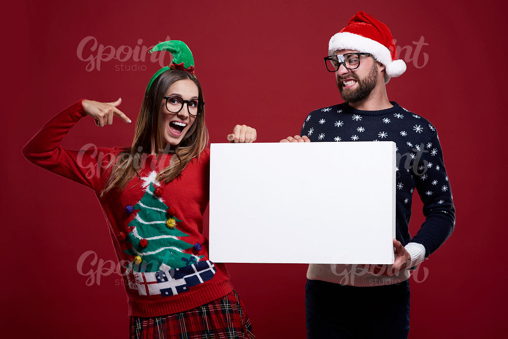 Pointing on placard in christmas clothes