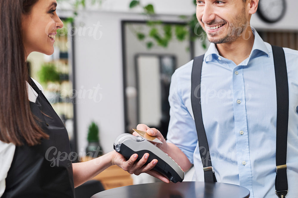 Pleased customer paying by credit card in hair salon