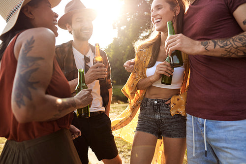 Group of young friends spending time outdoors in the summer and drinking beer