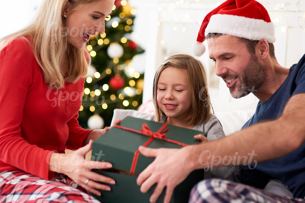 Family starting Christmas from opening gifts in bed