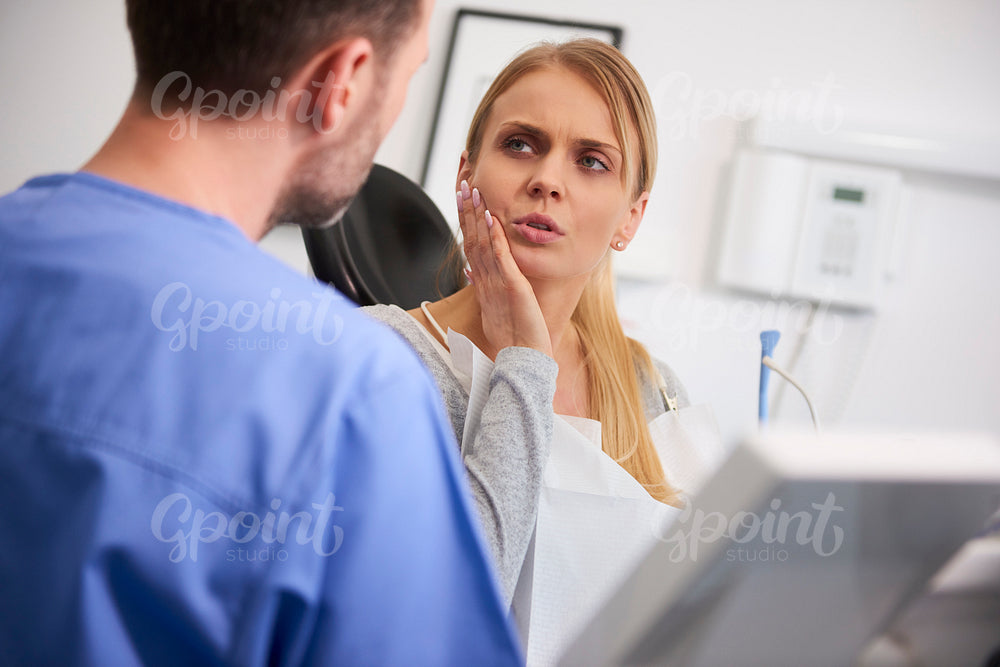 Woman with toothache talking to dentist