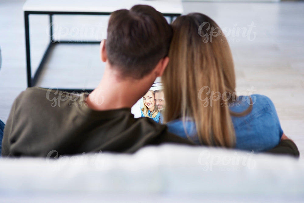 Rear view of loving couple watching photos on the tablet