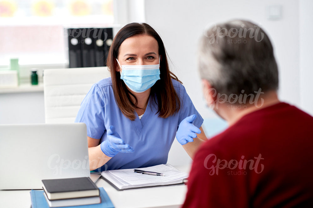 Female doctor in protective mask talking with a patient