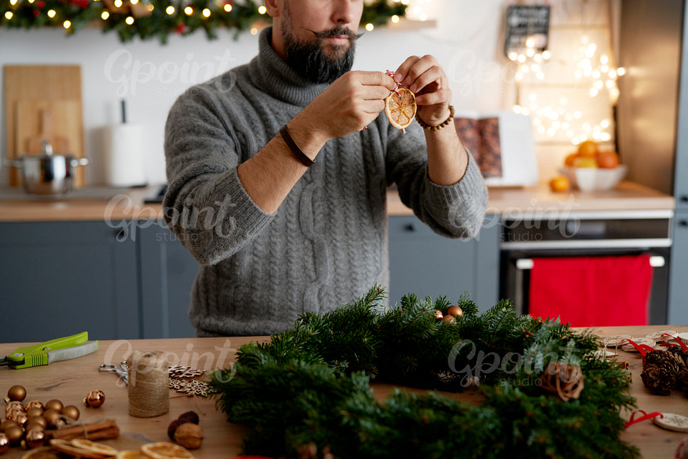 Man decorating Christmas wreath at home