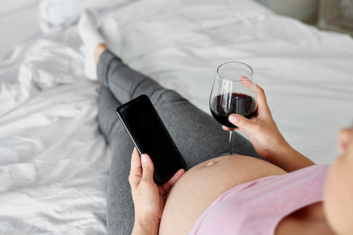 Woman pregnant drinking alcohol in bed