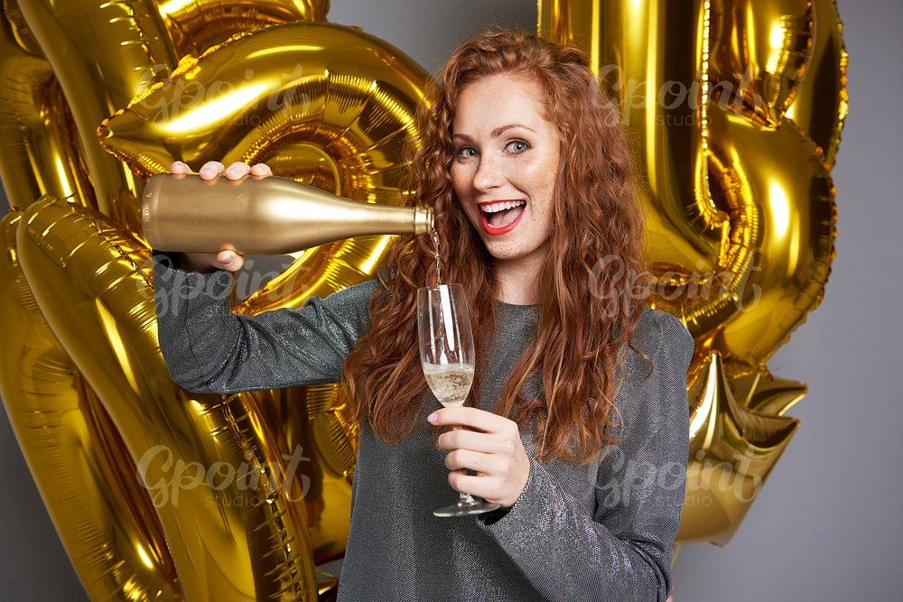 Screaming woman pouring champagne at studio shot