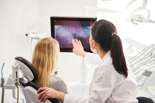 Rear view of dentist and patient looking at x-ray image