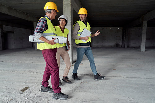 Three busy caucasian engineers walking across the construction site