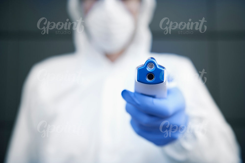 Technician in clean suit holding a non-contact thermometer