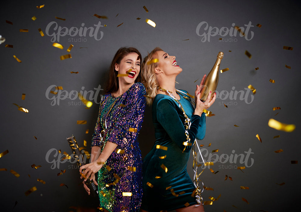 Women with champagne under shower of confetti