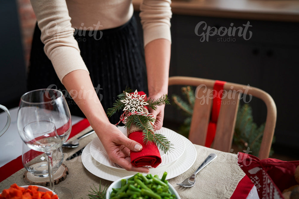 Woman preparing table for Christmas dinner