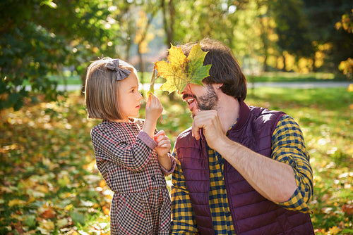 Father and daughter picking autumnal leafs