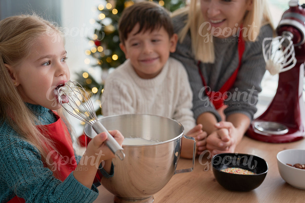 Girl tasting sugar paste during baking with family