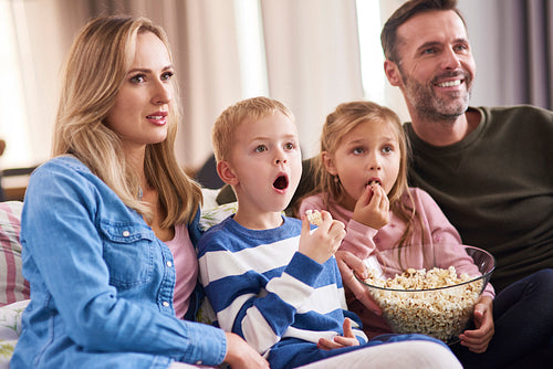 Family with two children watching TV in living room