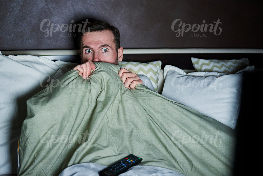 Scared man watching horror movies at night