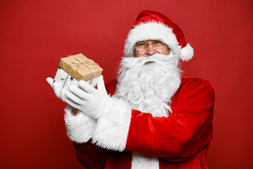 Smiling caucasian Santa Claus holding Christmas present