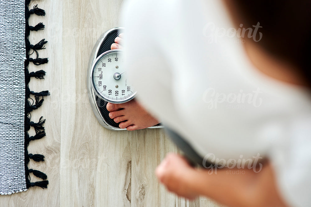 Horizontal image of woman standing on a bathroom scale
