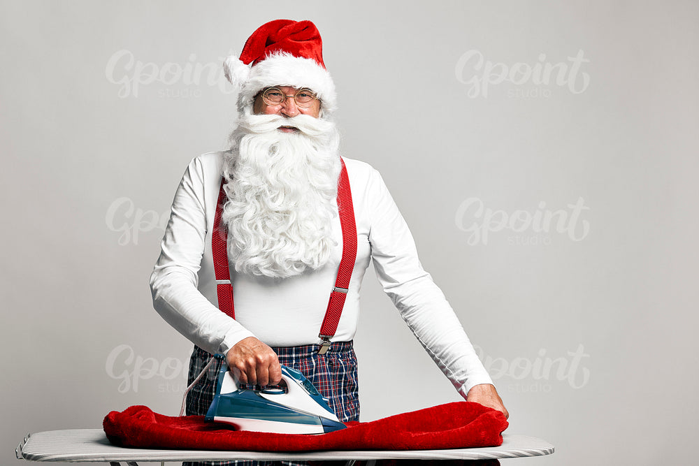 Caucasian Santa Claus ironing trousers for Christmas 