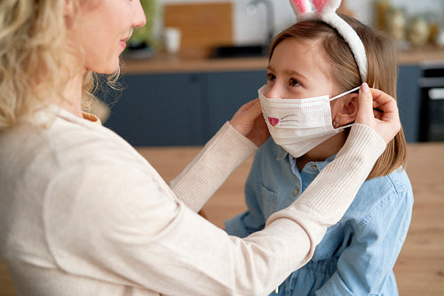 Mother applying on a protective face mask for her daughter