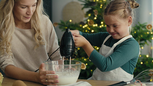 Caucasian mother and daughter preparing baking using electric mixer in the kitchen before Christmas