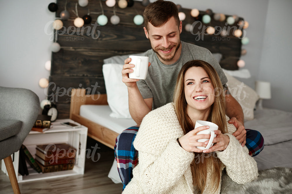 Cheerful couple with coffee enjoying at bedroom