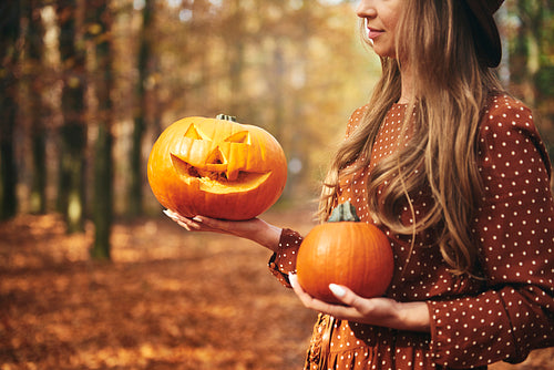 Woman holding halloween pumpkin in autumn forest