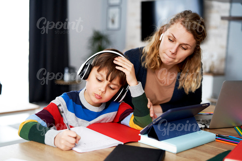 Mother working and helping her son with homework