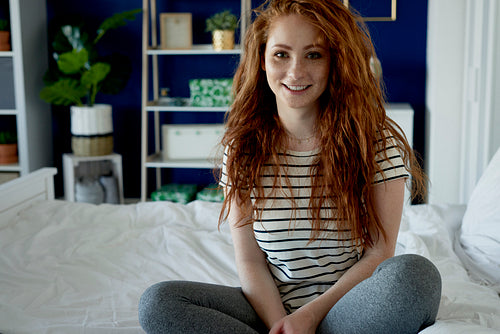 Portrait of redhead woman sitting on bed
