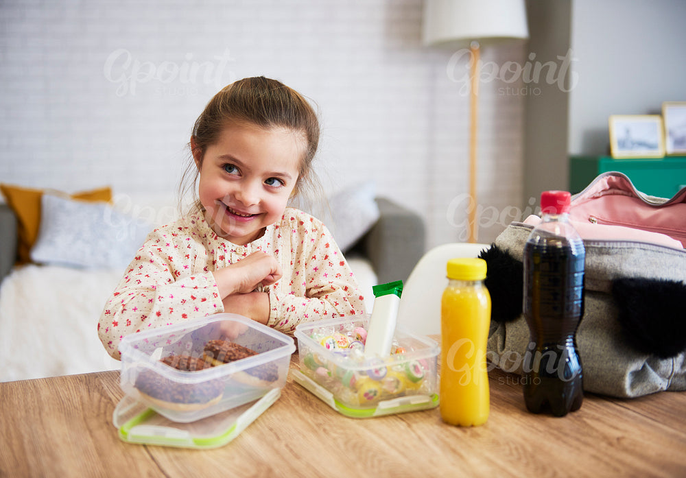 Happy child preparing lunch box with sweets
