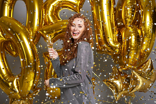 Woman drinking champagne under shower of confetti