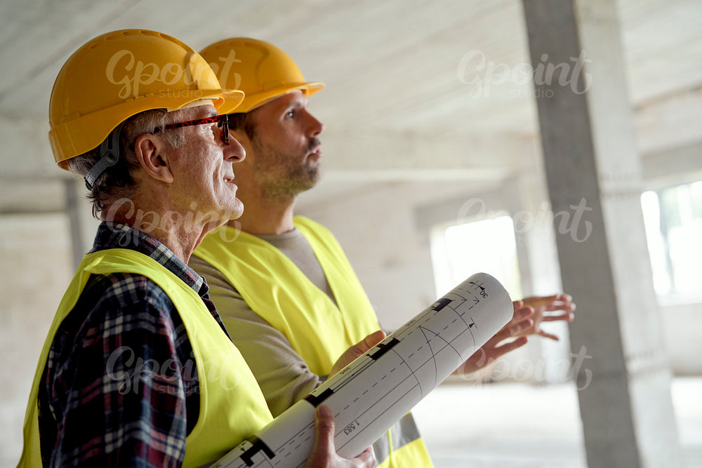 Close up side view of two caucasian engineers discussing on construction site