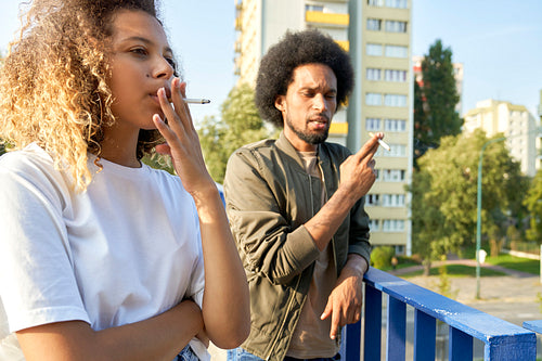 Two young people standing and smoking cigarette
