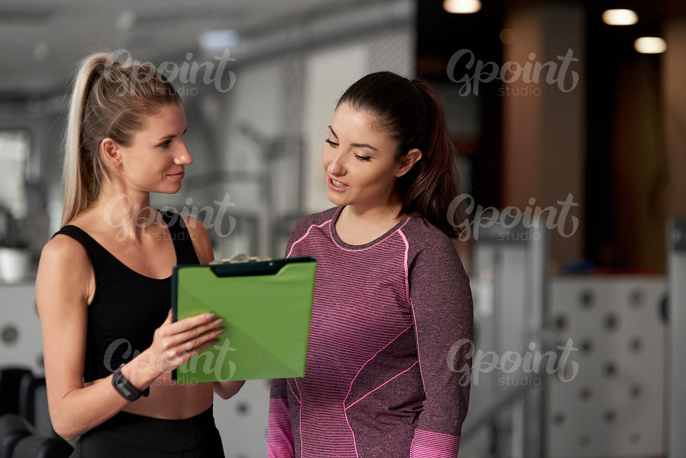 Fitness instructor and woman talking at gym
