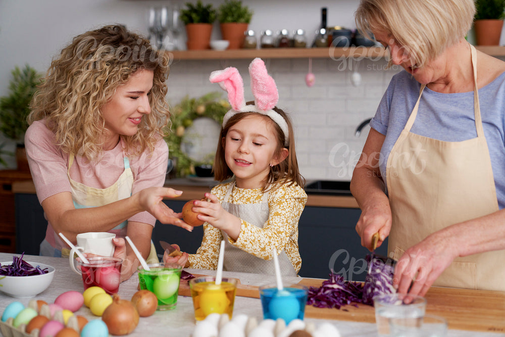 Little girl with family preparing natural dyes for coloring eggs