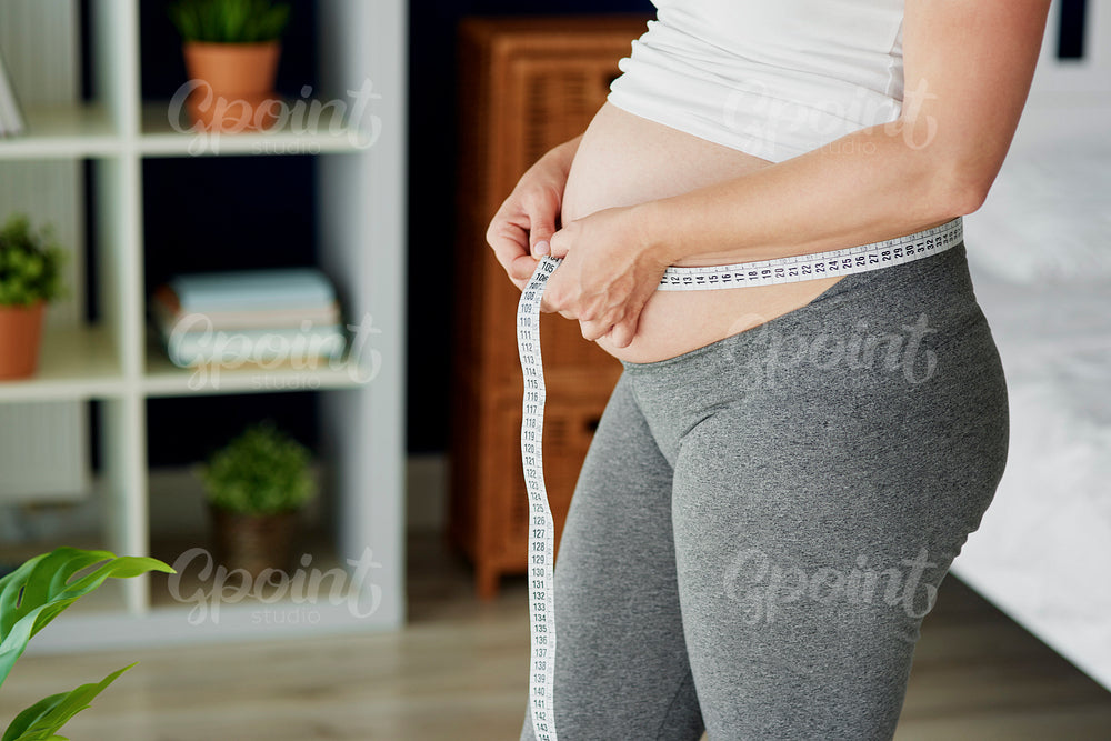 Pregnant woman checking the measure of the abdomen