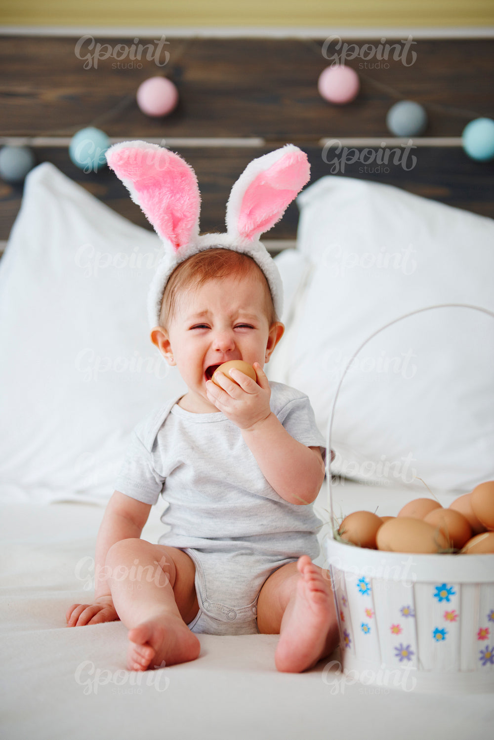 Crying baby eating an egg in bed