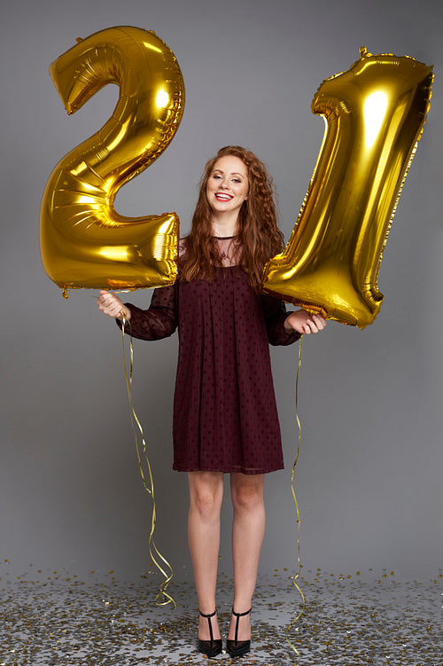 Happy young woman with golden balloons celebrating her birthday