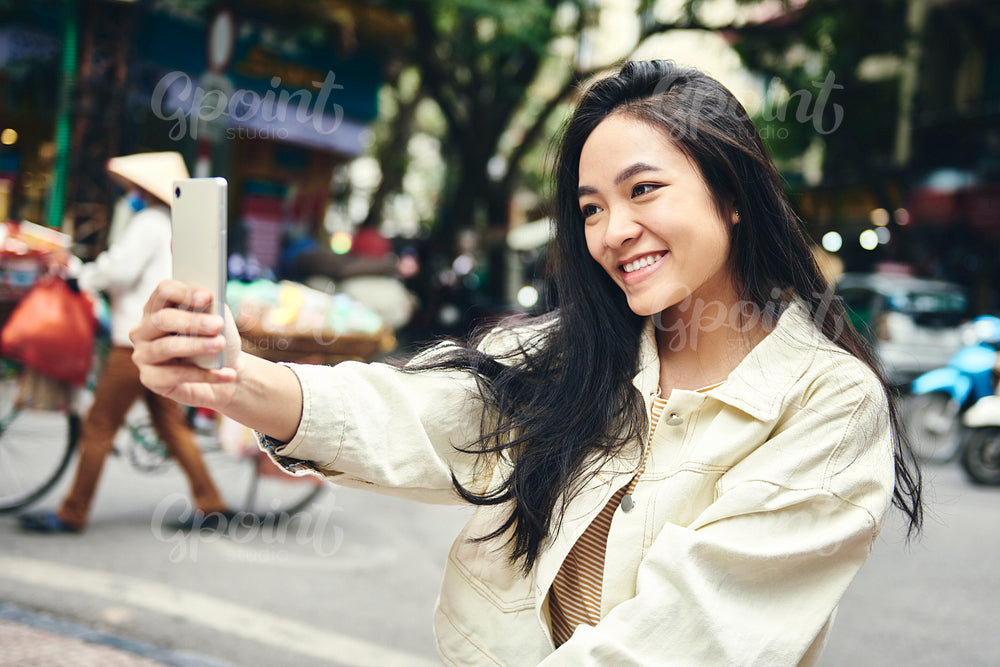 Young Vietnamese woman taking a selfie on the street