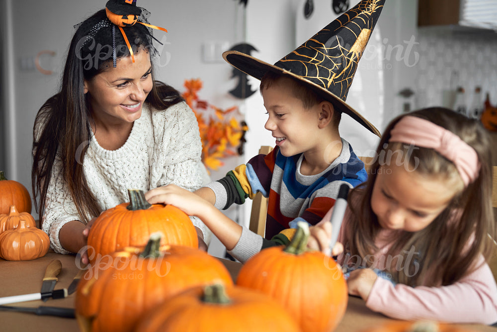 Mom with kids preparing pumpkins for Halloween 