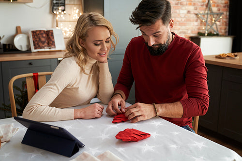 Couple learning to fold Christmas napkins