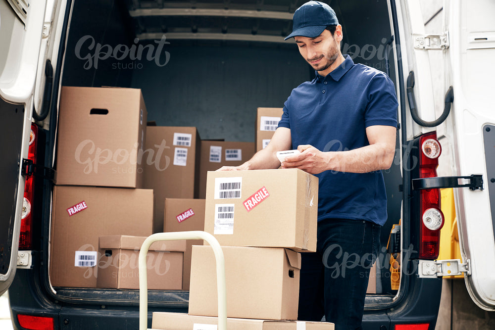 Smiling courier checks parcels on the hand truck