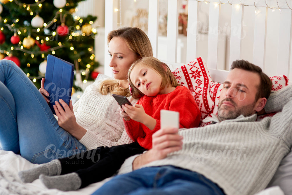 Bored family using mobile phone in bed at Christmas