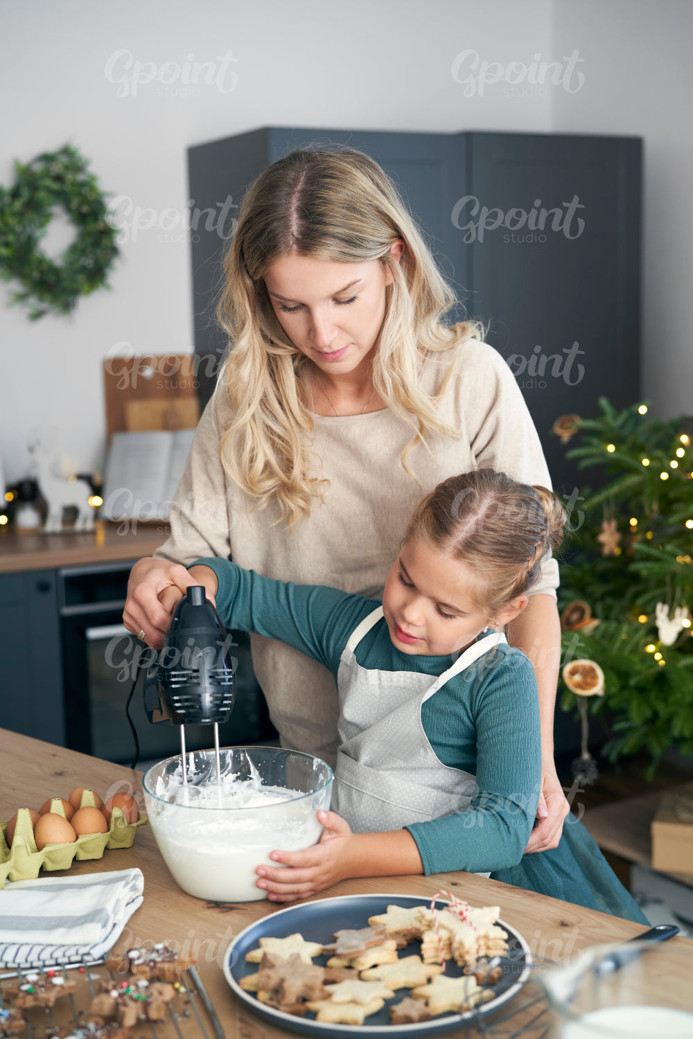 Caucasian mother and daughter preparing baking using electric mixer in the kitchen before Christmas