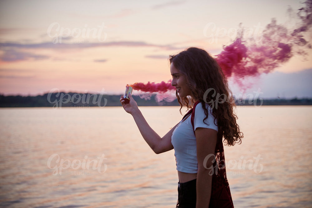 Beautiful young woman  having fun smoke bomb