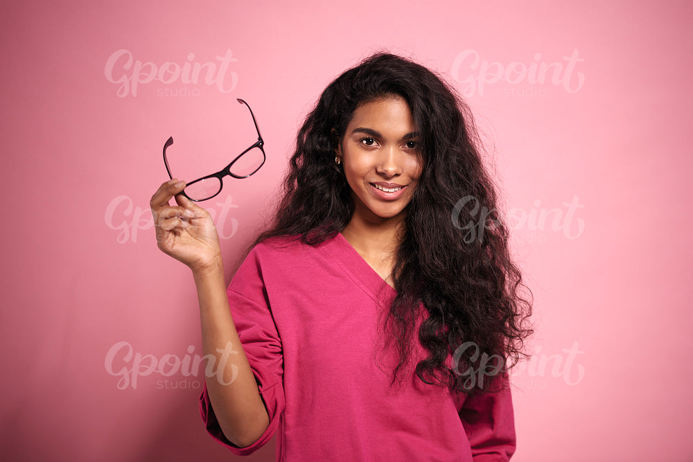 Beautiful African woman holding eyeglasses in hand in studio shot.
