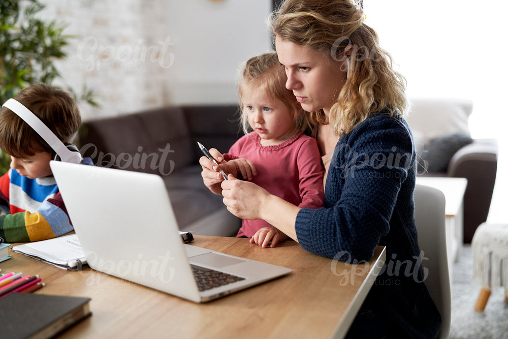 Mother during home office with little daughter on her lap