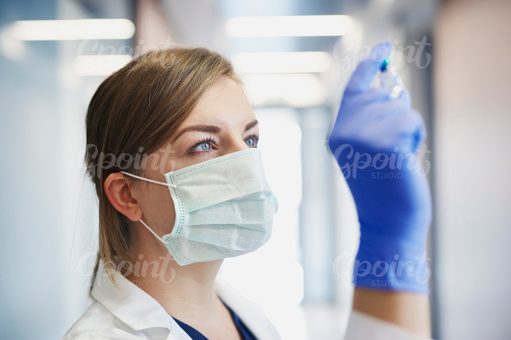 Doctor in protective mask with an ampule in hand